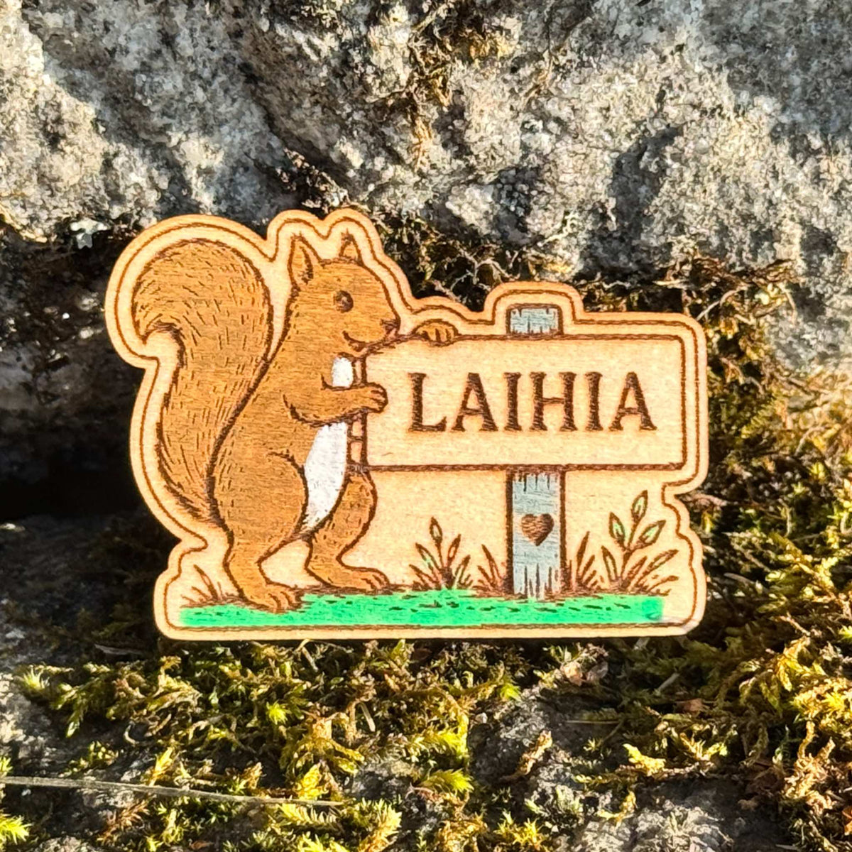 Maalattu puinen jääkaappimagneetti, jossa orava seisoo Laihia-kyltin vieressä ja alareunassa on vihreitä kasviaiheita.