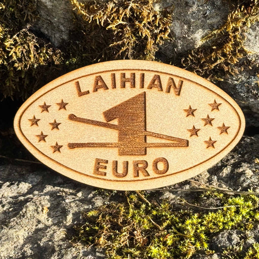 Soikea puinen Laihian euro -jääkaappimagneetti, jossa on suuri numero 1, tähtikuvioita ja kaiverrettu teksti Laihian euro.