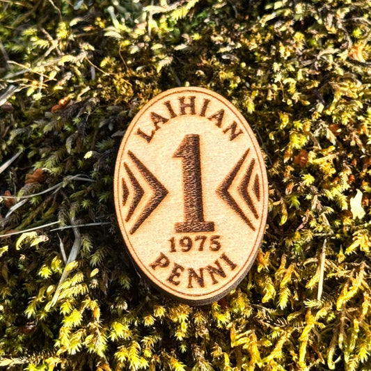 Soikea puinen Laihian penni -jääkaappimagneetti, jossa on numero 1, vuosiluku 1975 ja kaiverrettu teksti.
